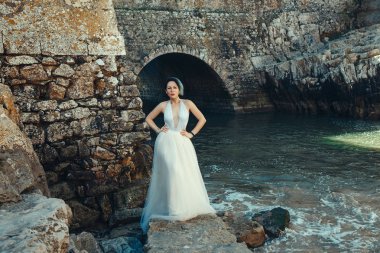 Beyaz elbise giyen güzel manken denizin yanında poz