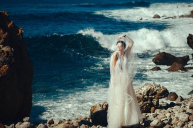 Beyaz elbise giyen güzel manken denizin yanında poz