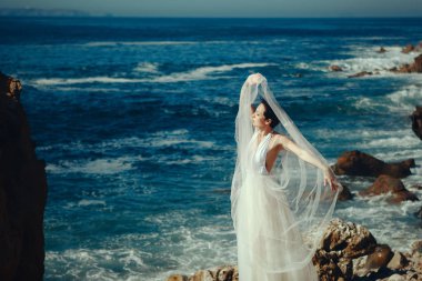 Beyaz elbise giyen güzel manken denizin yanında poz