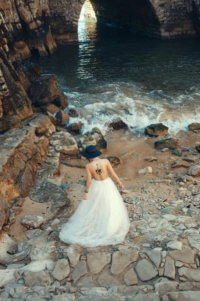 白いドレスを着た美しいモデルが海の横でポーズをとっている — ストック写真