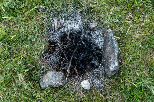 Die Asche eines Feuers im Gras. Frühjahrspause mit Schaschlik in der Natur. Umweltschutz — Stockfoto