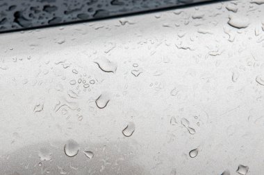 Arabanın yüzeyine saydam yağmur damlaları düşer.