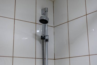 Beyaz fayanslardan oluşan bir arka planda duş başlığı. Otel odasında su tesisatı.