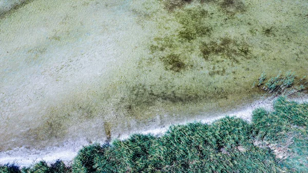 Vista superior de un hermoso lago poco profundo y su costa con arena y hierba — Foto de Stock