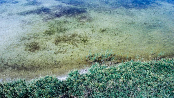 Vista dall'alto di un bellissimo lago poco profondo e la sua costa con sabbia ed erba — Foto Stock