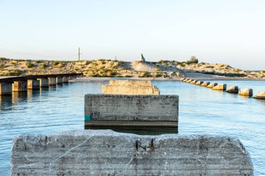 Bir kıyıdan diğerine bir köprüye karşı dar deniz ve kalıntıları.