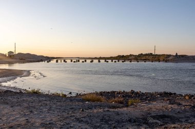 Bir kıyıdan diğerine bir köprüye karşı dar deniz ve kalıntıları.