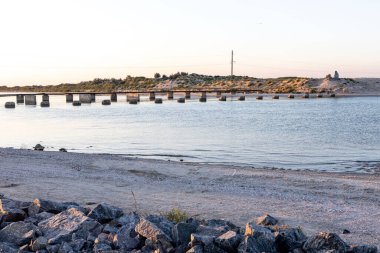 Bir kıyıdan diğerine bir köprüye karşı dar deniz ve kalıntıları.