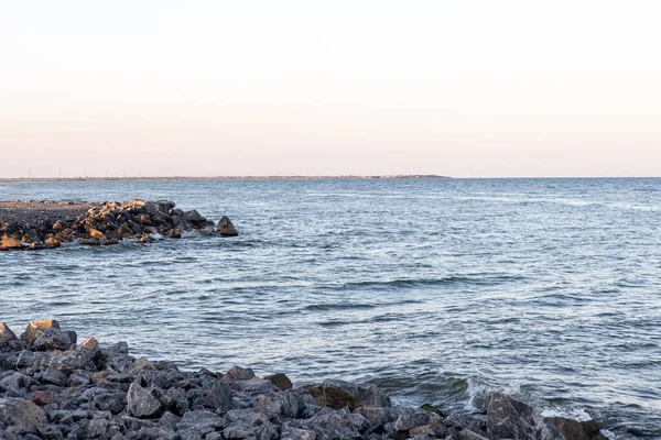 Кам'яний і піщаний берег з хвилями під час заходу сонця — стокове фото