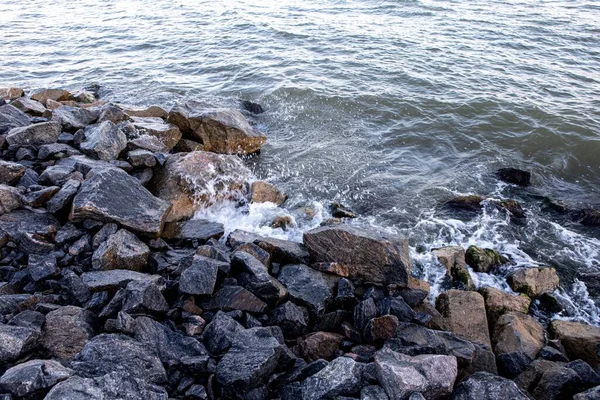 Stone and sand seashore with waves in the sunset light — Stock Photo, Image