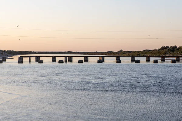 Mar estrecho contra y restos de un puente de una orilla a otra — Foto de Stock