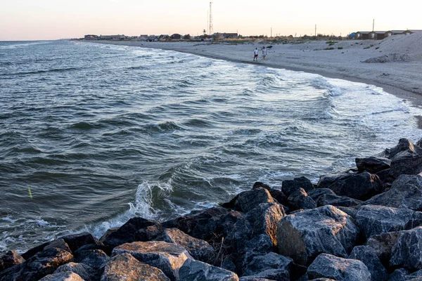 Piedra y arena a orillas del mar con olas en la luz del atardecer —  Fotos de Stock