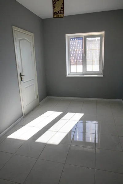 door, window and light spot in a gray empty room. New housing without furniture.