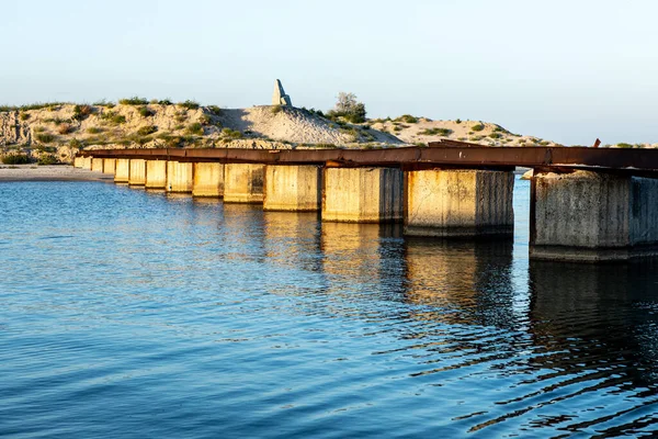 Mar estreito contra e restos de uma ponte de um banco para outro Imagem De Stock