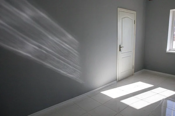 Porta, janela e ponto de luz em uma sala vazia cinza. Novo alojamento sem mobília. — Fotografia de Stock