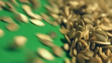 Yeşil bir arka plan üzerinde Kabak Çekirdeği kabuklu. Yakın çekim. Dikey pan. 2 Shots1. Kabak haddeleme aşağı (soldan sağa) yeşil bir arka plan üzerinde tohum ve uzay frame.2 doldurur. Dikey (yukarıdan aşağıya) yavaş panorama.