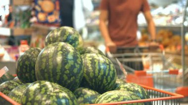 Süpermarkette karpuz meyve kutusu. O zaman erkekler ellerini karpuz almak ve potaya birak adam sepeti ile karpuz kutusuyla taşır.