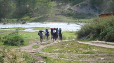 Turistler dağ Nehri yakınında dağlarda trekking gidin. Sırt çantaları turistlerle Nehri Dağ yolunda gitmek.
