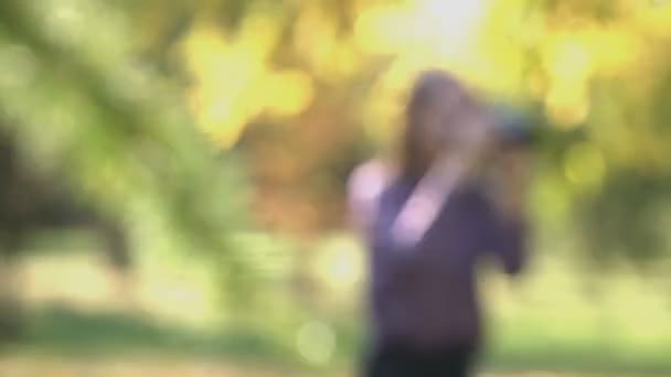 公園で女の子を傷つけます Shots 公園で写真をカメラと少女が立っています 彼女は自然に写真を撮る 女の子に支店から移動します 少女は 撮影ポイントを探しています 風が吹く太陽輝く — ストック動画