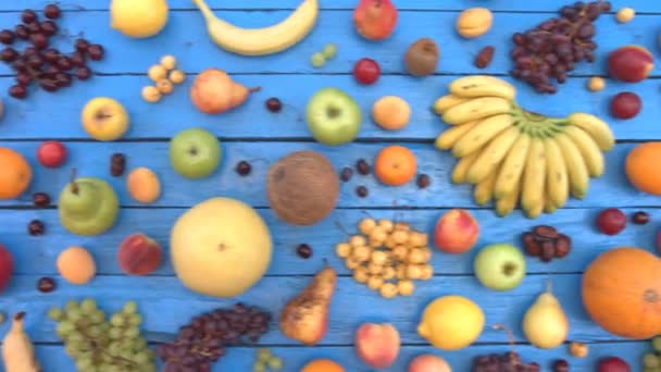 青の生態学的背景に果物 平面図です カラフルな木製エコ背景に様々 な果物があります ここでは りんご バナナ さくらんぼ ネクタリン ザクロ — ストック動画