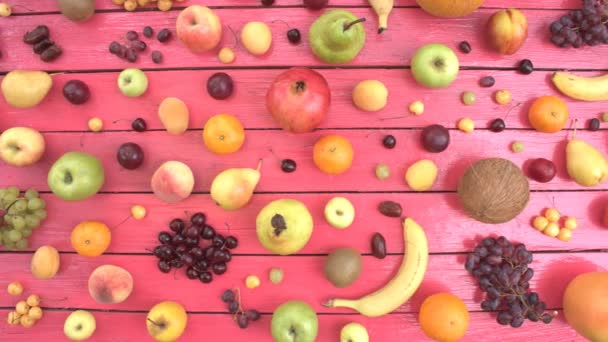 ピンクの生態学的背景に果物 平面図です ピンクの木製エコ背景に様々 な果物があります ここでは さくらんぼ りんご 日フルーツ バナナ ネクタリン — ストック動画