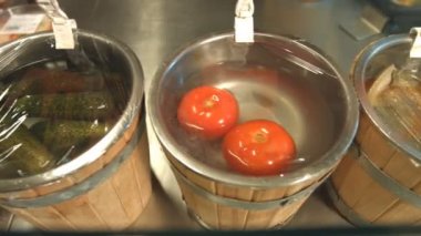 Turşusu domates ve salatalık fıçıları içinde vardır. Turşusu domates ve salatalık fıçıları bir sıraya dizilmiş. 2Kamera soldan raf boyunca sağa doğru taşır.