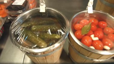 Turşusu domates ve salatalık fıçıları içinde vardır. Turşusu domates ve salatalık fıçıları bir sıraya dizilmiş. 2Kamera soldan raf boyunca sağa doğru hareket eder ve kiraz domateslere durur.