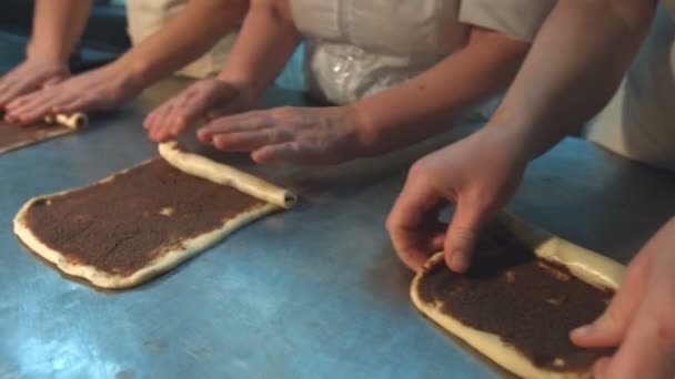糕点厨师准备烘焙菜肴 三个糖果工人在一张特殊的桌子上做糕点 他们推出面团制作罂粟种子的辫子 从右到左 平底锅 — 图库视频影像