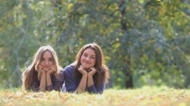 Kızlar Park. Rüzgar gibi geçti. Kızlar çim yavaşça kameraya bakıyor. Rüzgar eser. Olumlu amotions. İki kız arasında dostluk.