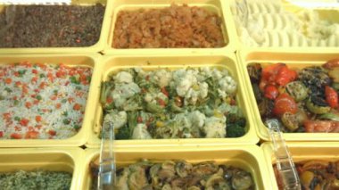 Yan yemekler süpermarkette. Farklı yan yemekler vitrinde yer alan: haşlanmış sebze, sote pilav, ızgara sebze, Avrupa pilav, mantar, lahana, buğday, patates püresi.