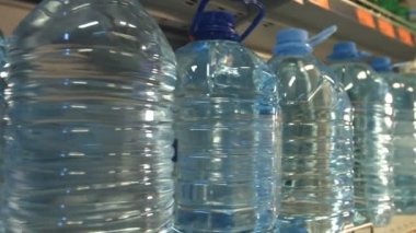 Şişe suyu. Su şişeleri mağaza raf üzerinde durmak. El bir şişe alır.