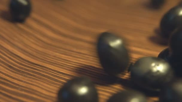 茶色の木製の背景にブラック オリーブ Shots Slow モーション 閉じる オリーブ下に転がっている 左から右 に茶色の木製 Background — ストック動画