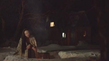 Ateşin yanında birayla birçift. 2 atış. Kız ateşin yanında tek başına oturur sonra adam gelir ve ona bir bardak bira getirir. Duman ve kıvılcımlar birbirinden ayrı uçar. Arka bahçede geceleri rahatlayın. Kış. Alkollü içecek.