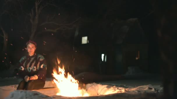 火の下の少女女の子は強い火の中で涙を流している 火花が飛び散る彼女は暖かい服を着ている クルミ セーター ジーンズ それは通りの夜です 家は背景に立っている — ストック動画