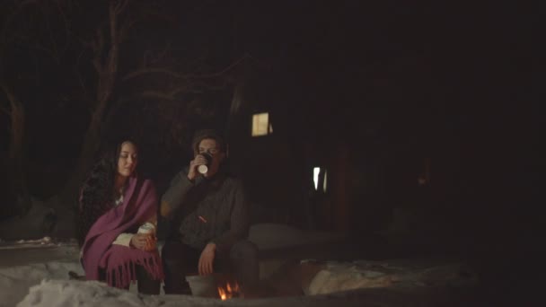 小伙子们正在用纸杯喝着热饮 还在火上浇油 晚上在后院用火把放轻松 茶和咖啡 — 图库视频影像