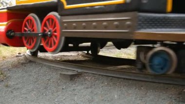Çocuk treni - eğlence parkında cazibe. Çocuklar için eğlence parkında çocuk demiryolu. Tren raylara çıkıyor. Tren kameradan uzaklaşıyor. Alt görünüm. 
