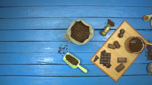 顶部视图 慢动作 桌子上是烤咖啡豆在袋子里 研磨咖啡在碗里 速溶咖啡在碟子 桌子上还有不同的巧克力产品 摄像机从左向右移动 — 图库视频影像