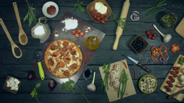 生态黑色背景的超级肉比萨 停止运动 肉比萨在生态桌上自行盘旋 披萨由食材组成 桌子上还有许多其他产品 用于烹饪和吃披萨 — 图库视频影像