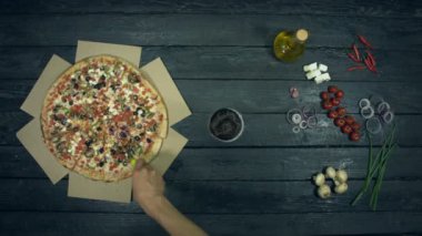 Ekolojik siyah arka planda vejetaryen pizza. Adam pizzakeser sonra bir bardak bira ve pizza parçası alır. Pizza farklı dolgu ile: domates, biber, mantar, çeşitli peynir, zeytin. Pizza yemek için masada birçok ürün vardır.