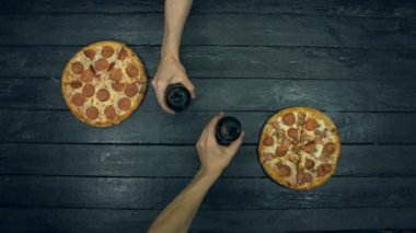 Ekolojik siyah arka planda vejetaryen pizza. Adam şişeden cama bira döker. Pizza farklı dolgu ile: domates, biber, mantar, çeşitli peynir, zeytin. Pizza yemek için masada birçok ürün vardır.