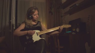Ev kayıt stüdyosu. Yavaş çekim. Genç bir kadın elektro gitar çalıyor..