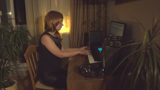 ホームレコーディングスタジオ ある若い女性がコンピュータのMidiキーボードを使って音楽を書きます そして 彼女は記録された結果に耳を傾ける — ストック動画