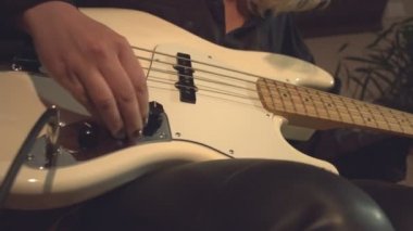 Ev kayıt stüdyosu. 2 Çekim.1. Close. Kamera soldan sağa doğru hareket eder. Kadın el bas konektörü.2 ses kablosunun fişini takılır. Kamera sağdan sola hareket eder. Bir kadın rock müzisyeni bilgisayara bas yazar.