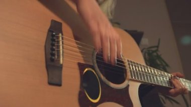 Ev kayıt stüdyosu. 2 Çekim.1. Close. Kadın el akustik gitar konektörü.2 ses kablosu fişi takılır. Bir kadın gitar çalıyor. Kamera soldan sağa doğru hareket eder.