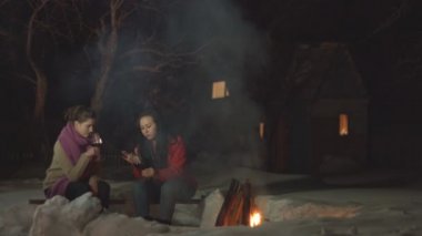 Ateşin yanında iki kadeh şarabı olan kızlar. Ateşin yanında iki kadeh kırmızı şarapla oturan kızlar. Alkollü içkiyle rahatlarlar..