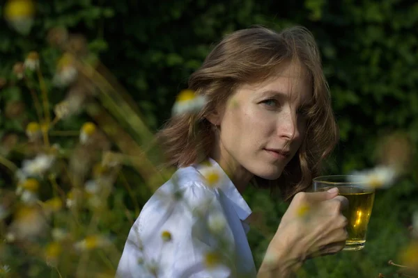Doğada çay içmek. Genç bir kadın papatya çayı içiyor..
