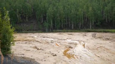 Çalışan fabrika yüzünden çevre kirliliği. Su, perith metalinin drenajı nedeniyle turuncuya döndü. Su ve orman fabrikadan gelen zararlı emisyonlarla kirlenmiş..