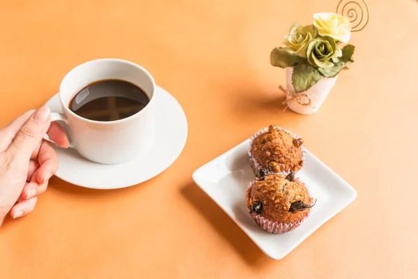 Black coffee and insect food banana cupcake - Hands holding black coffee in a white cup and insect food in a banana cupcake. Healthy meal high protein diet concept.