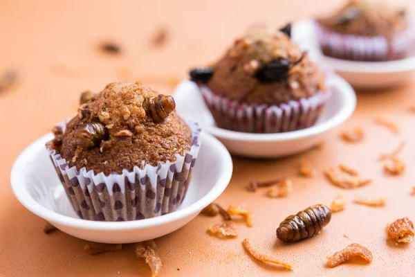 Banana cupcakes with insect foods - Banana cupcakes with insect foods on the small white bowl and crispy shallots fried on orange tablecloth background. Healthy meal high protein diet concept. Close-up, Selective focus.