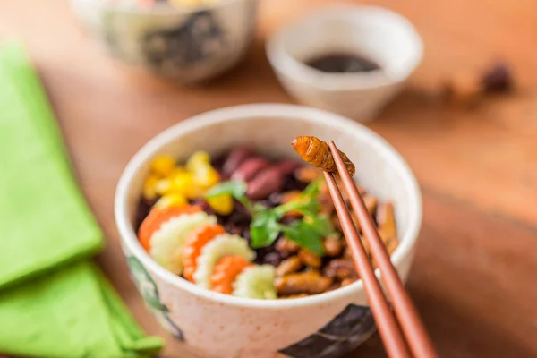 Insects food with Rice Berry - Cricket insects, Corn, Red bean, Carrot, Cucumber with Rice Berry in a retro bowl and green table napkin. Healthy meal high protein diet concept. Selective focus.